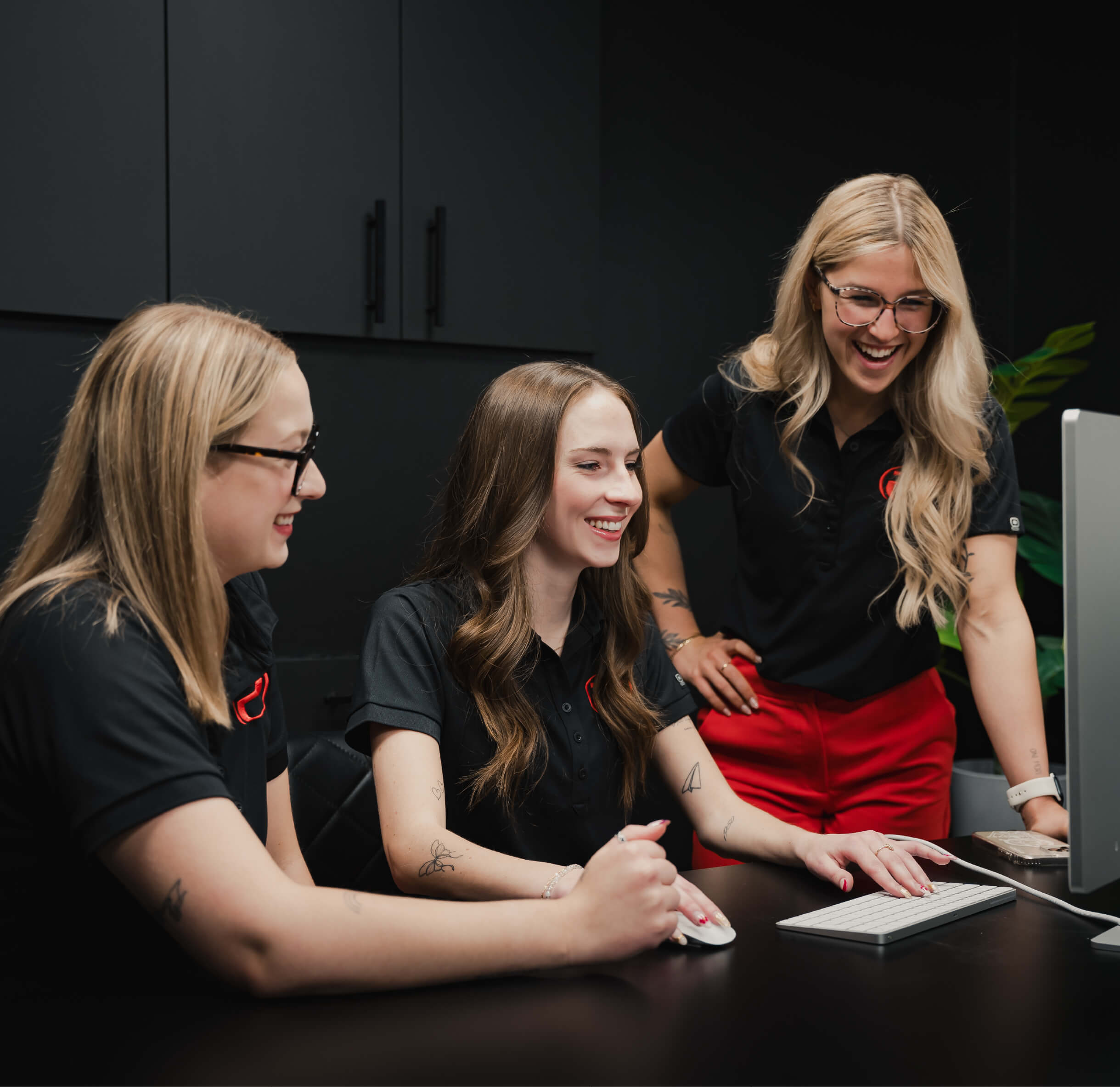 Trois membres de l’équipe marketing du ProGym travaillent ensemble devant un ordinateur